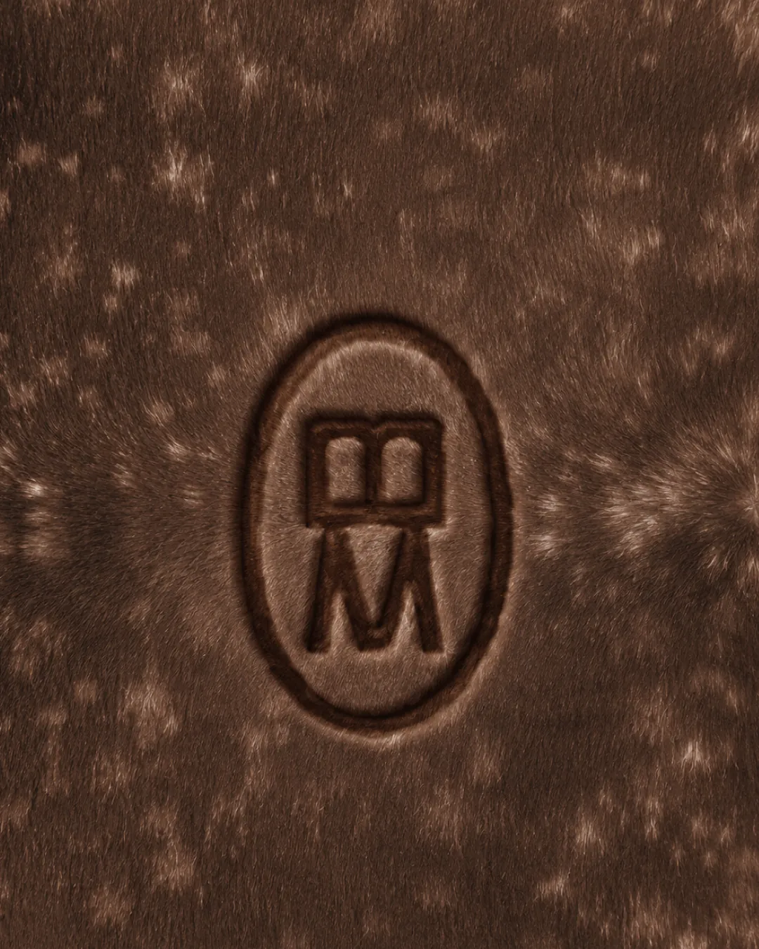 Sello del monograma BM en relieve sobre piel